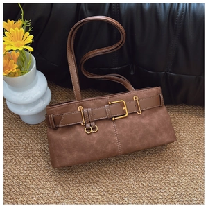 Détail d'un sac porté épaule en daim marron avec boucle de ceinture décorative et finitions dorées