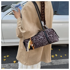 Detail of leopard print cylinder bag with decorative wooden beads and leather strap