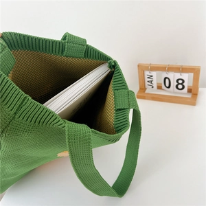 Green knit tote bag with yellow daisy pattern showing spacious interior for books
