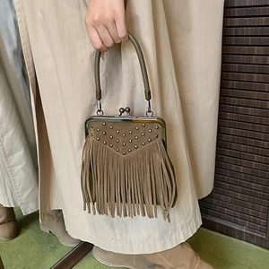 Detail of tan suede tote bag with fringe, silver rivets and classic kiss-lock closure