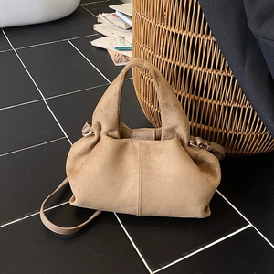 Camel suede cloud dumpling bag with shoulder strap in a stylish French lifestyle setting