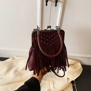 Detail of burgundy fringe handbag featuring V-shaped rivets and retro metal clasp closure