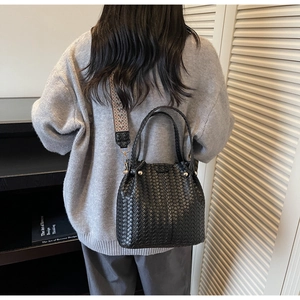 Detail of black woven bucket bag with metallic studs and patterned jacquard strap