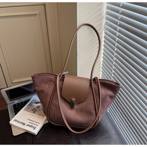 Detail of dark brown suede tote bag with leather strap and metal buckle in a home setting