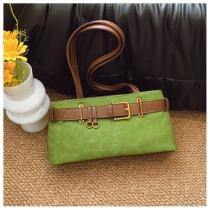 Détail d'un sac sous le bras en daim vert herbe avec une boucle de ceinture en cuir marron
