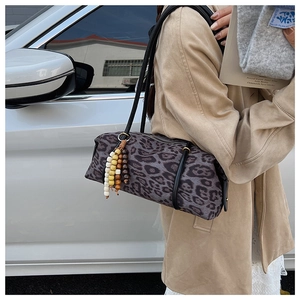 Detail of leopard print cylindrical shoulder bag with beaded tassel and wood charms