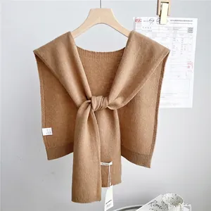 Detail view of camel knit wool shawl with twist knot design on wooden hanger