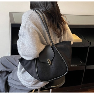 Close-up of black suede tote bag with gold metal buckle and dual slim shoulder straps