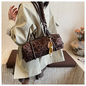 Detail of vintage leopard print cylinder bag with stylish beaded charm on long strap