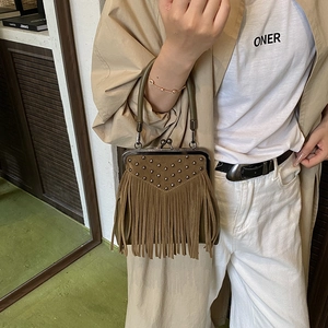 Detail of brown suede tassel bag with V-shaped metal studs and green handle decoration