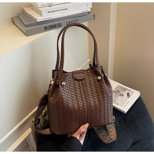 Detail of woven brown bucket bag featuring a textured pattern and patterned wide strap