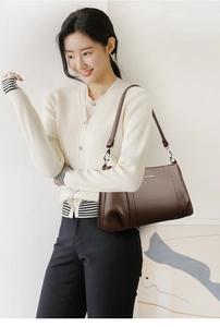 Detail of a brown lychee pattern leather shoulder bag with silver hardware and branding