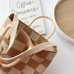 Brown and beige checkered knit tote bag with round ivory resin handles on white desk