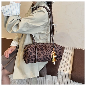 Detail of leopard print barrel bag with brown leather handles and beaded charm decor