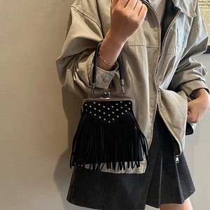 Detail of a vintage black handbag with silver rivets, fringe tassels and metal frame clasp