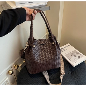 Detail of dark brown woven bucket bag with vintage gold rivets and ethnic pattern strap