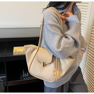 Detail of beige tote bag with gold buckle closure and leather strap on model