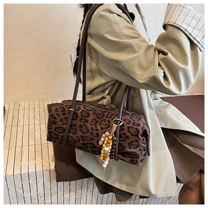 Close-up of leopard print barrel bag with beaded charm on a stylish trench coat model