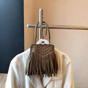 Detail of vintage olive green suede handbag with V-shaped rivets and long fringe tassels
