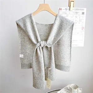 Detail of light gray wool knit shawl with ribbed edges and elegant front tie closure