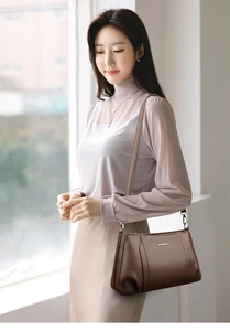 Close-up of brown textured leather handbag with brand logo and soft natural lighting