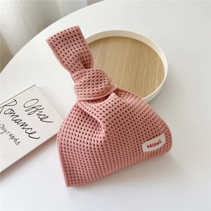 Detail der rosa hohl gestrickten Tasche mit Hildi Webetikett auf weißem Tisch