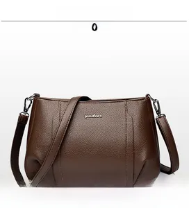Close-up of brown litchi pattern leather texture and silver metal brand logo on bag