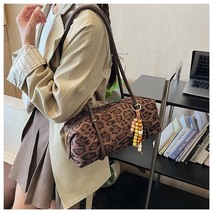 Detail of leopard print cylinder bag featuring colorful bead tassel and dual straps