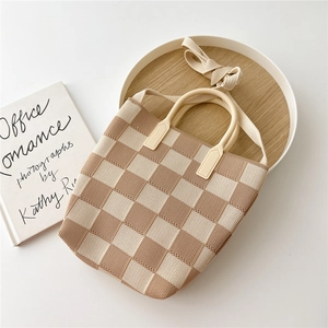 Detail shot of a knit checkerboard tote bag with round handles on a white table