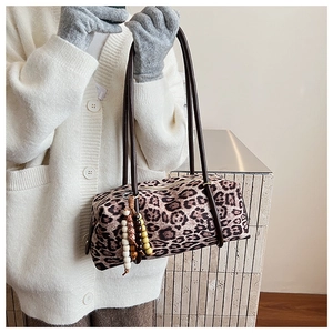 Detail view of leopard print cylinder handbag with wooden beads on soft winter cardigan