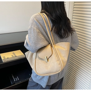Detail view of beige suede tote bag featuring a gold metal twist lock and minimalist design
