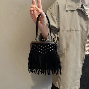 Detail of black suede handbag with silver rivets, long tassels and retro metal frame