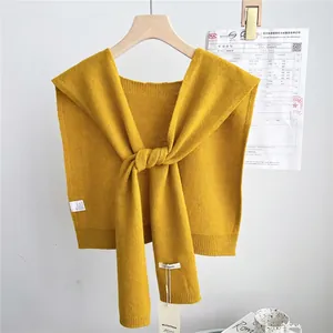 Detail of ginger yellow knitted wool shawl with button closure and 100% wool texture