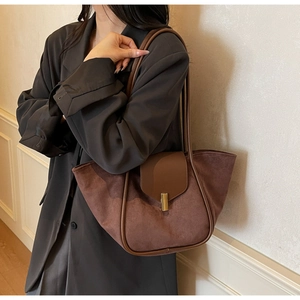 Detailed close-up of dark brown suede tote bag with gold buckle and leather trim strap