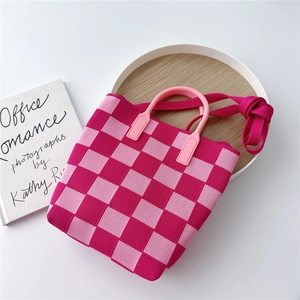 Detail of pink checkered knit bucket bag with rounded handles on wooden display tray