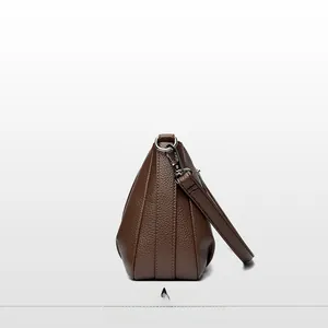 Detail view of brown pebbled leather crossbody bag with silver hardware and accordion side