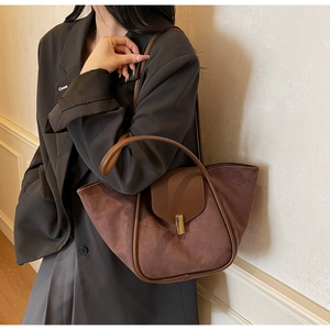 Brown suede tote bag detail with golden metal lock and leather strap on model