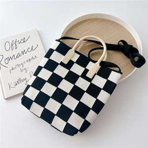 Close-up of black and white checkered knit tote bag with cream round handles and strap
