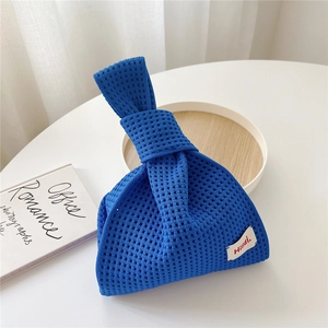 Detailansicht der blauen Stricktasche mit Netzmuster und weißem Logo-Etikett-Tag