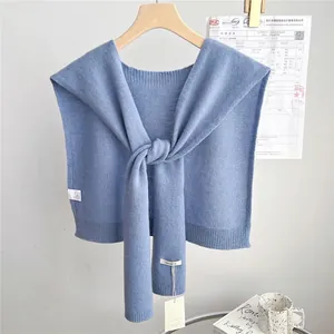 Detailed view of light blue wool shawl with 100% wool tag on wooden hanger