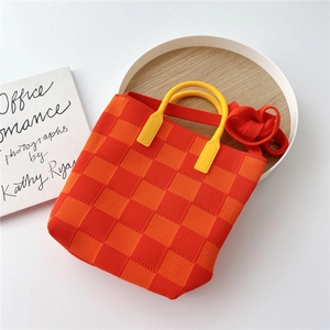 Detail of checkered knit tote with yellow handle and strap on a wooden tray