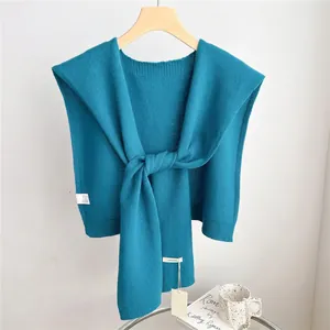 Detailed view of 100% wool teal knitted shawl texture on a wooden hanger with soft fabric