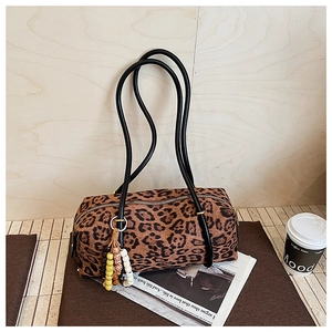 Leopard print cylinder handbag with beaded tassel detail on a wooden surface
