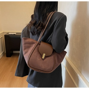 Detail of dark brown suede tote bag with golden metal buckle and smooth leather stitching