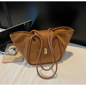 Close-up of brown suede and leather tote bag with elegant gold metal lock on desk