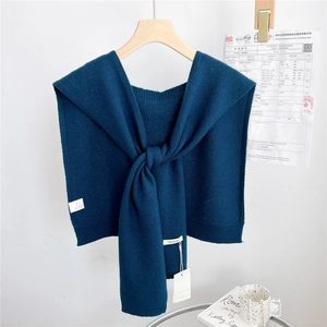 Detail view of dark teal knitted wool shawl with knot design and wool material label