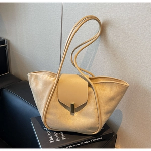 Close-up of beige suede tote bag featuring a gold metal lock and leather shoulder strap
