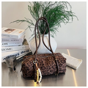 Detail of leopard print cylinder bag with brown strap and colorful beaded tassel charm