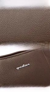 Detailed view of dark brown pebbled leather texture with silver yadier metal logo