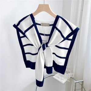 Close-up of striped knit shawl with brand tags hanging on a wooden hanger in a bright room